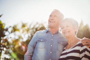 Elderly couple embracing each other in the sunshine.