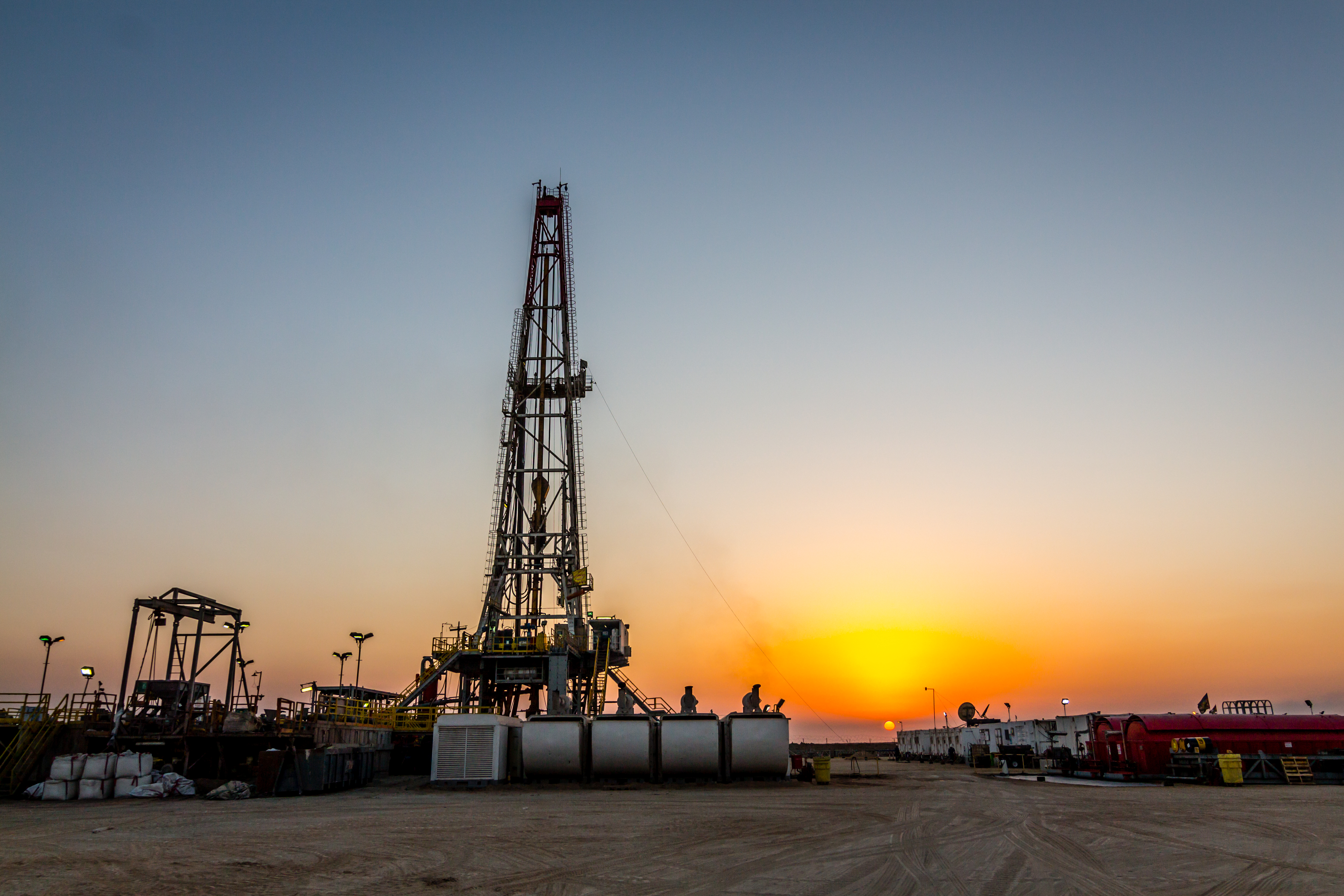 An oil drilling rig with a sunset in the background.