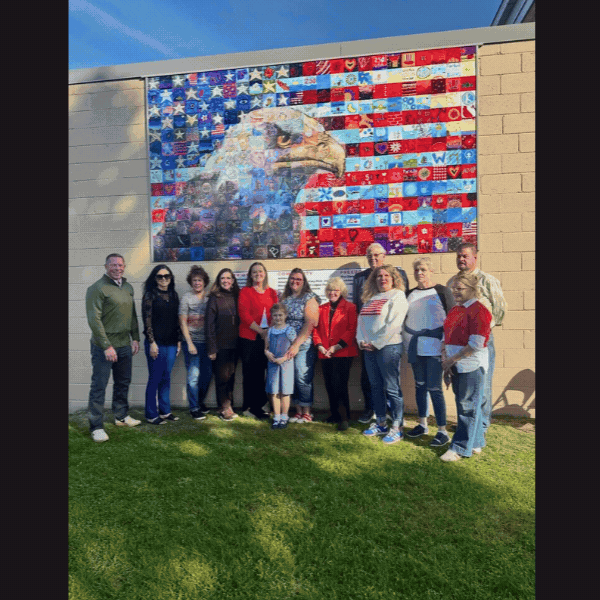 Slideshow: Sen. Baker with Wyoming County residents in front of outdoor mural made of many colorful square tiles that form a stylized bald eagle on the Tunkhannock Area School District Administration Building.